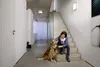 A woman and her dog are sitting on a staircase in a modern home. Produktbild-Vorschau
