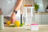 A person is preparing fruit in a kitchen next to a water filter pitcher and a small container. Náhled obrázku produktu
