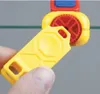 A hand holding a yellow tool near a red and yellow device with a red gear. Produktbild-Vorschau