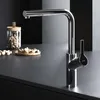 A modern kitchen faucet with a sleek design is shown on a dark countertop, with a glass jar of nuts and a small wooden plate of nuts in the background. Produktbild-Vorschau