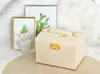 A beige jewelry box with a key and handle, placed on a straw mat in front of two framed cactus prints. Podgląd zdjęcia produktu