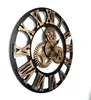 A large, decorative wall clock with Roman numerals and exposed gears, mounted against a white wall. Produktbild-Vorschau