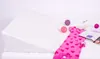 A white wedge mattress is shown on a bed, with a pink baby outfit, two decorative balls, and an open magazine placed on the bed next to it. Náhled obrázku produktu