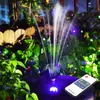 A solar-powered water fountain with LED lights is shown in a garden setting at night, with a remote control in the foreground. Podgląd zdjęcia produktu