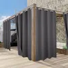 Outdoor curtains hanging on a wooden pergola structure next to a stone wall and a seating area. Produktbild-Vorschau