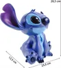 A blue Stitch figurine is shown sitting, with dimensions indicated by lines and text. Produktbild-Vorschau