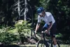 A man cycling on a road surrounded by trees. Anteprima dell’immagine prodotto