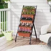A vertical planter with multiple tiers of flowers on a wooden deck, next to a white railing and a white sofa. Náhled obrázku produktu