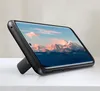 A black smartphone case with a built-in stand is shown on a white surface, displaying a mountain landscape on the phone screen. Náhled obrázku produktu