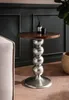A round wooden side table with a metallic, spherical base is placed next to a sofa in a room with dark green paneled walls. Voir les images du produit