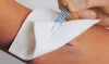 A close-up of a person's arm with a wound being dressed with a sterile gauze pad. Podgląd zdjęcia produktu