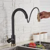 A black and gold kitchen faucet with a pull-down sprayer is shown in use, with water running into a sink containing an apple and grapes. Produktbild-Vorschau