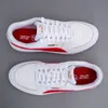 A top-down view of two white Puma sneakers with red accents. Produktbild-Vorschau