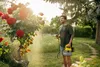 A man is spraying a rose bush in a garden with a Kärcher pressure sprayer. Produktbild-Vorschau