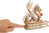 A finger is pressing a button on the base of a wooden dragon model. Anteprima dell’immagine prodotto