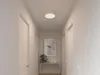 A hallway with doors and a ceiling light. Voir les images du produit