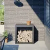 A firewood rack filled with logs sits on a patio next to a brick wall. Anteprima dell’immagine prodotto