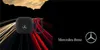 A black AirPods case with the Mercedes-Benz logo is shown against a background of blurred car light trails. Voir les images du produit