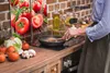 A person is cooking in a kitchen, with a collage of tomatoes on the left side of the image. Produktbild-Vorschau