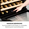 A hand is shown touching the control panel of a wine cooler, with bottles visible inside. Produktbild-Vorschau