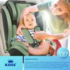 A woman is securing a baby in a green car seat. Produktbild-Vorschau