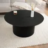 A dark wood coffee table with a ribbed base sits on a textured white rug, with a hint of a couch in the background. Voir les images du produit