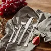A set of cutlery is arranged on a gray cloth, with grapes and a fig nearby, suggesting a dining or food preparation setting. Anteprima dell’immagine prodotto
