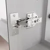 A close-up view of a cabinet hinge attached to a cabinet door. Náhled obrázku produktu