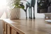 A close-up view of a wooden surface, likely a tabletop or dresser, with a potted plant and a decorative deer figurine in the background. Voir les images du produit