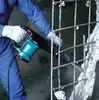 A person in blue overalls and white gloves is using a demolition hammer to break concrete and rebar. Anteprima dell’immagine prodotto