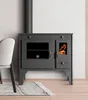 A dark gray wood-burning stove with a glass door showing flames, placed in a room with a chair and a rug. Náhled obrázku produktu