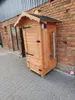 A wooden smoker box with a black roof sits on a cobblestone patio next to a brick wall. Anteprima dell’immagine prodotto