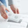 Hands installing a white double electrical outlet into a white brick-like textured surface. Produktbild-Vorschau