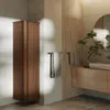 A modern bathroom with a tall, dark brown cabinet, a wooden vanity with a stone sink, and a round mirror. Anteprima dell’immagine prodotto