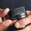 A close-up shot of hands holding a black applicator brush with bristles. Anteprima dell’immagine prodotto