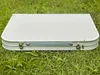 A closed, silver folding table is lying on green grass. Anteprima dell’immagine prodotto