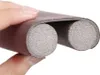 A hand is holding a brown foam door draft stopper. Náhled obrázku produktu