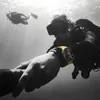 Two divers underwater, one in the foreground showing off a yellow smartwatch. Produktbild-Vorschau