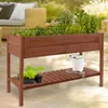 A wooden raised garden bed filled with various plants, placed on a wooden deck with outdoor furniture in the background. Produktbild-Vorschau