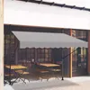 An outdoor cafe setting with tables and chairs under a gray awning. Náhled obrázku produktu