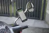 A smartphone with navigation displayed is mounted on a scooter's mirror. Anteprima dell’immagine prodotto