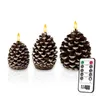 Three LED candles shaped like pinecones are displayed on a white background, with a remote control in the foreground. Produktbild-Vorschau