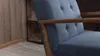 Close-up view of a blue armchair with wooden armrests and a wooden-paneled wall in the background. Produktbild-Vorschau