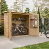 A wooden garden shed with two bicycles inside and one outside, set in a garden. Podgląd zdjęcia produktu