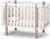 A baby crib with a mattress and padded sides, presented on a white background. Produktbild-Vorschau