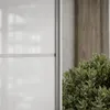 A close-up view of a white high-gloss cabinet door next to a green plant. Produktbild-Vorschau