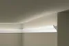 A white decorative molding is installed at the junction of a wall and a ceiling, with subtle lighting highlighting its profile. Produktbild-Vorschau