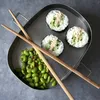 A top-down view of a sushi-making kit with sushi rolls and edamame beans on a metal tray. Náhled obrázku produktu