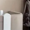 A close-up view of the edge of a baby crib with a teddy bear in the background. Produktbild-Vorschau