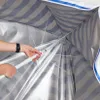 Close-up view of a person assembling a striped beach umbrella. Náhled obrázku produktu
